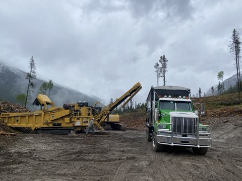 Chipper loading a truck on a wet mountain landing