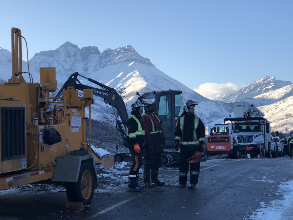 Rossco's crew with a whole-tree chipper, excavator and bucket trucks on a snowy mountain corridor