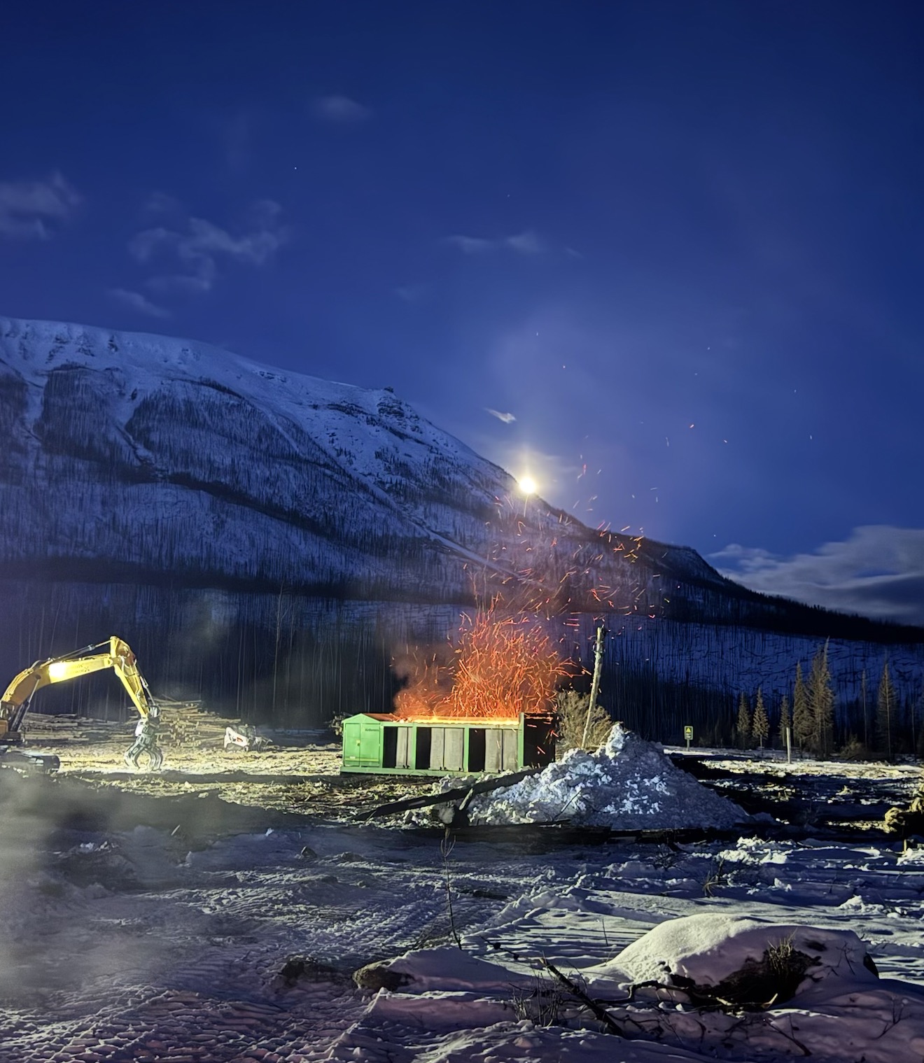 Night burn container operation below a snow-covered mountain